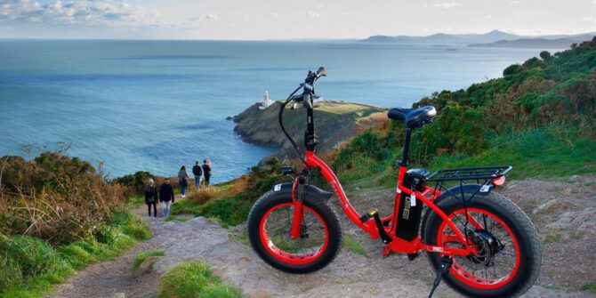 panoramic-ebike-tour-red-ebikes-with-cyclists-pausing-to-take-in-the-stunning-lighthouse-and-ocean-vistas-dublin-ireland
