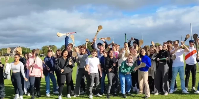 a large group of people participating in a hurling experience, a popular cultural activity for visitors to Ireland.