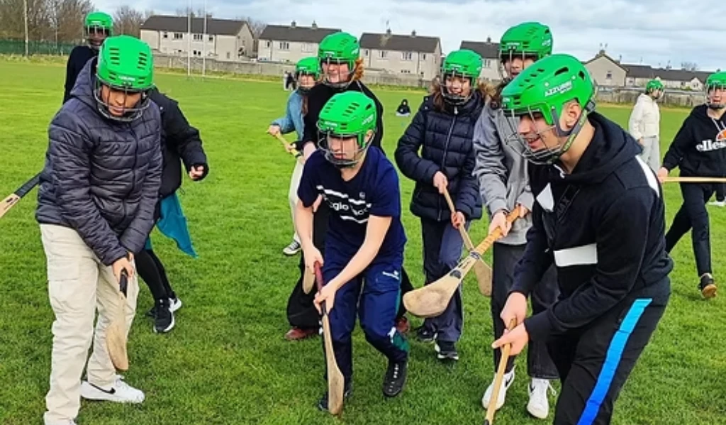 participants are learning to handle the hurley and compete for the sliotar (ball) on the ground.